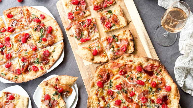 Rye flatbreads with prosciutto and raspberry on serving boards with wine