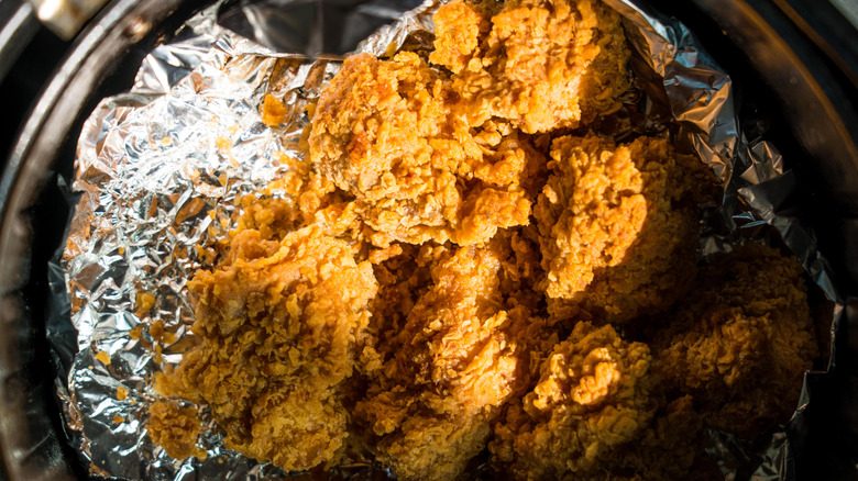Fried chicken in air fryer resting on aluminum foil