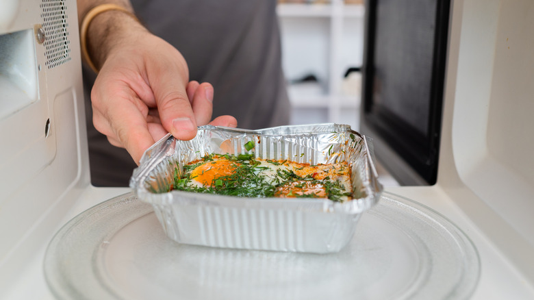 Placing meal in aluminum tray in microwave