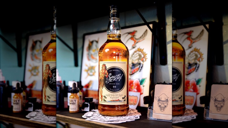 Bottle of Sailor Jerry in front of various tattoo designs