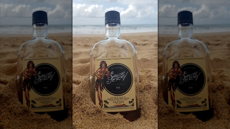 Bottle of Sailor Jerry rum in the sand on a beach in front of the ocean