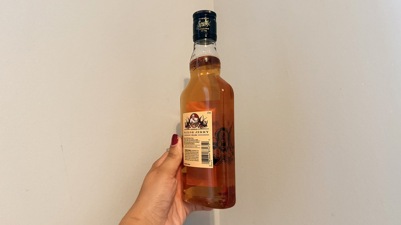 Hand holding a bottle of Sailor Jerry, with a peek at the back label