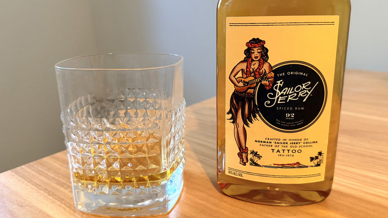 Close-up on a Sailor Jerry bottle's label next to a rocks glass