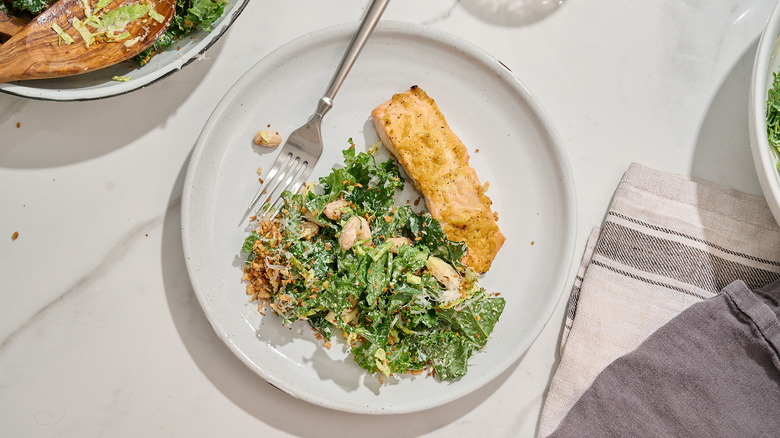 salmon and caesar salad on a plate with a fork
