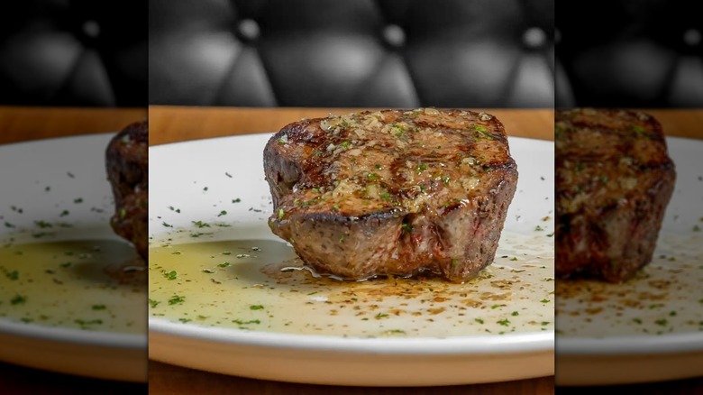 A steak topped with butter and herbs