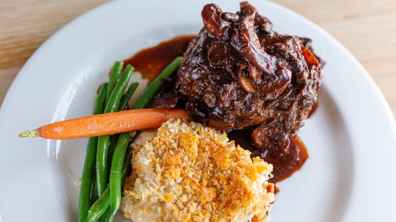 Short rib, mac & cheese, and vegetables on a white plate