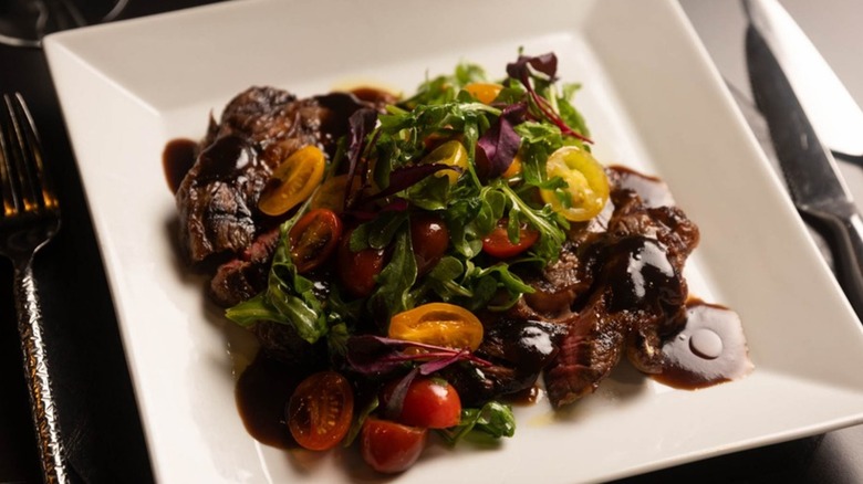 A salad topped with tender steak pieces