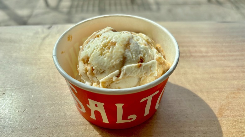 Cup of Salt & Straw Apple Cheddar Cinnamon Rolls ice cream on wooden surface