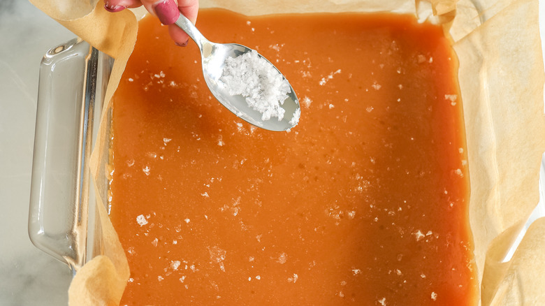 hand holding spoon of salt over candy