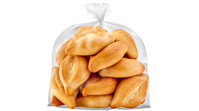 A clear bag filled with Bolillo rolls on white background