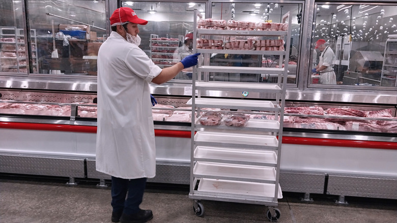 Costco butcher stocking meat display.