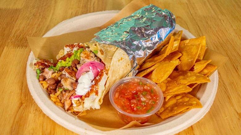 A grilled cheese burrito from El Gallo Giro on a paper plate with chips and salsa