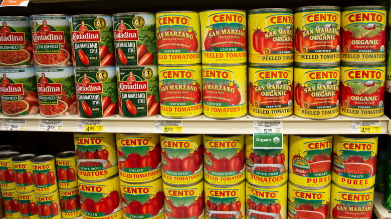 Cans of San Marzano tomatoes on a grocery store shelf including Cento brand certified and organic versions