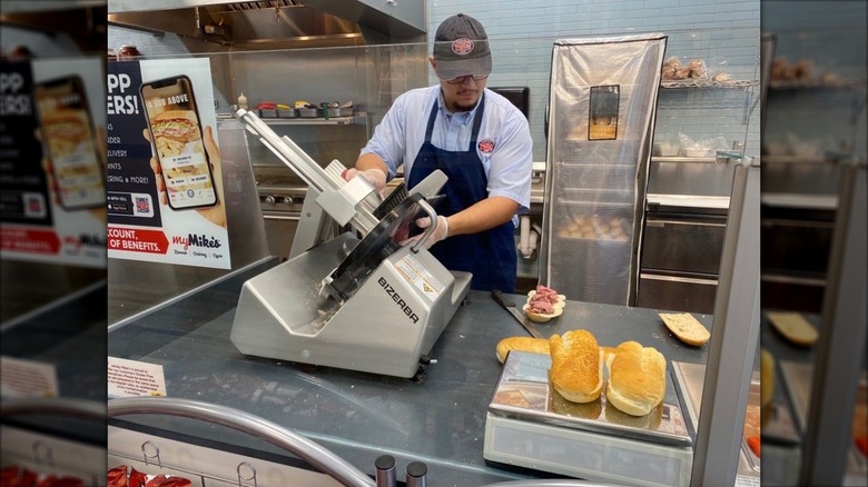 A Jersey Mike's employee slicing deli meat behind the counter