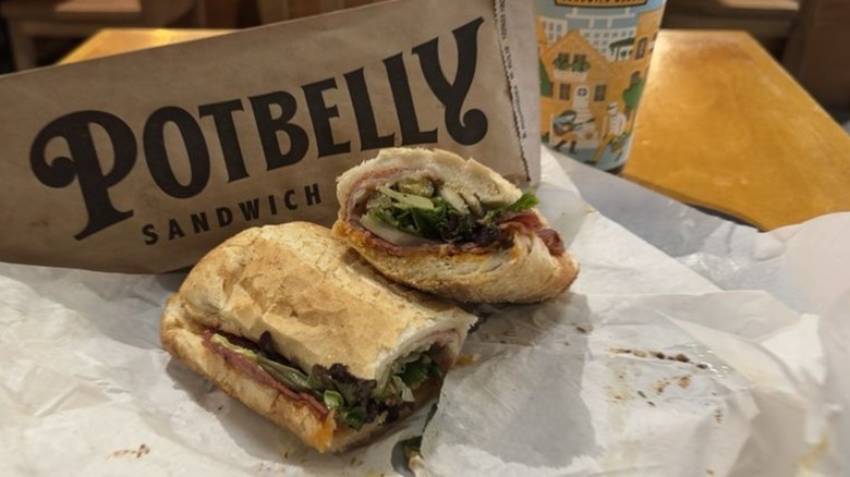 Potbelly sandwich cut in half on parchment paper with Potbelly paper bag in the background