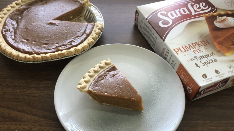 a slide of sara lee pumpkin pie on a plate next to the rest of the pie and the package