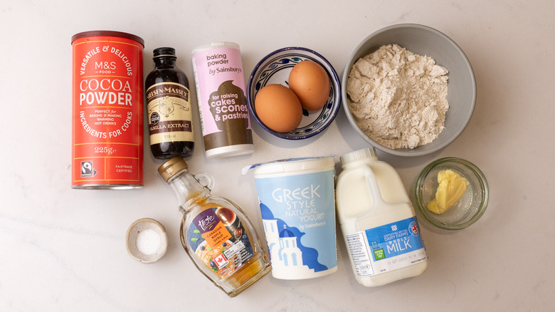 two eggs in bowl, container of Greek yogurt, and other high protein chocolate pancakes ingredients laid out