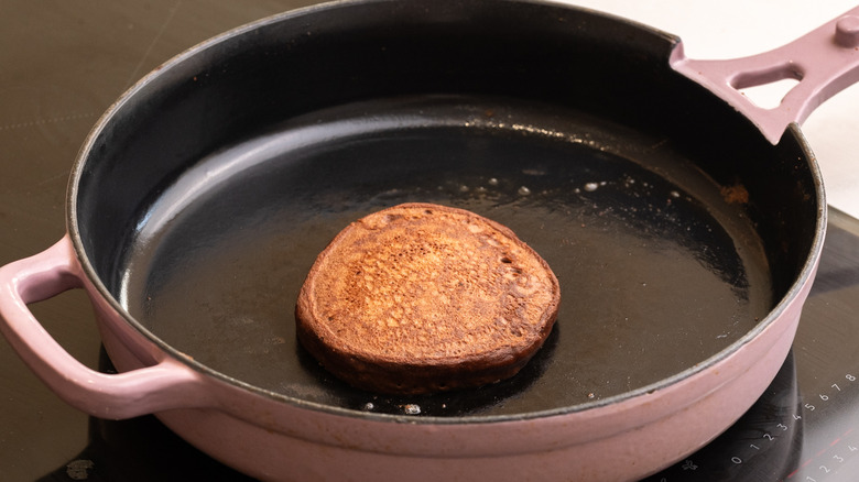 chocolate pancake cooking in greased pan on stovetop