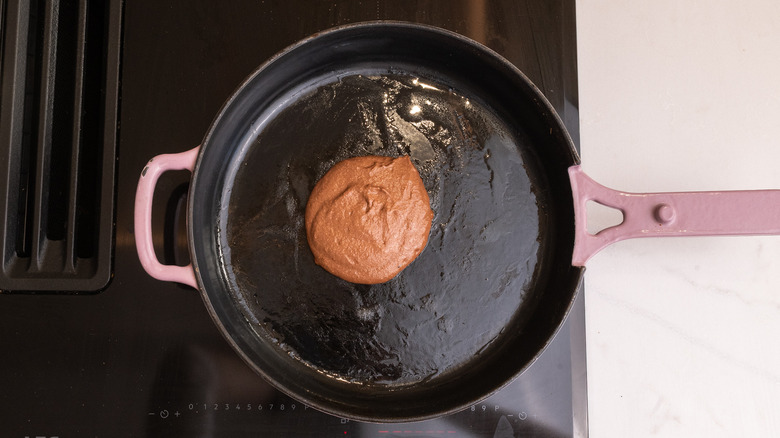 chocolate pancake cooking in greased pan on stovetop