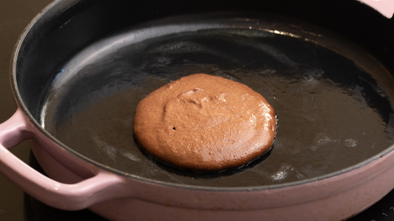 chocolate pancake batter cooking in greased pink pan