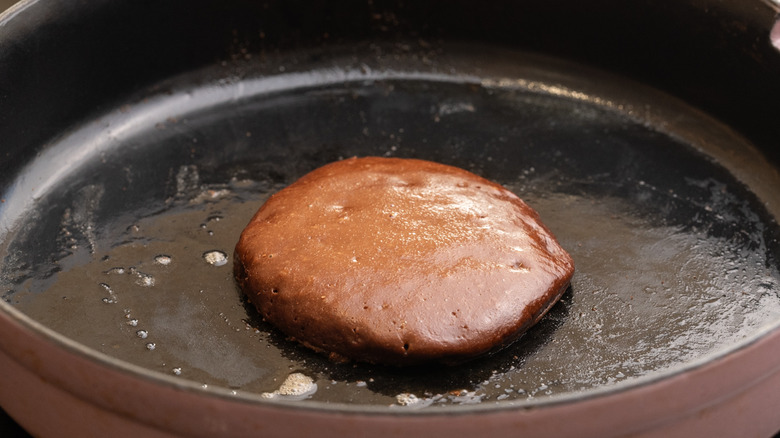 closeup of chocolate pancake cooking in greased pan