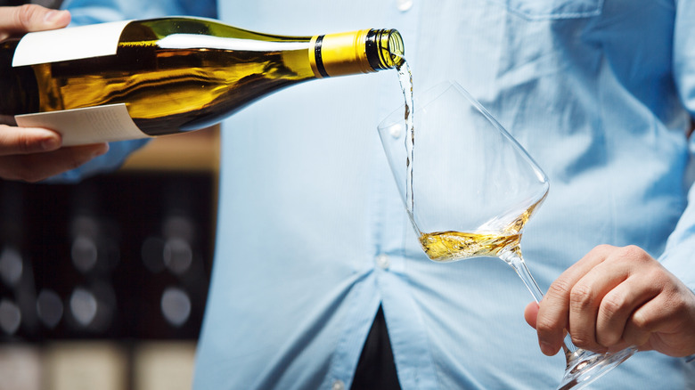 Foodie pouring white wine into a long-stemmed glass