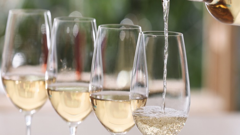 Image of pouring white wine into wine glasses.