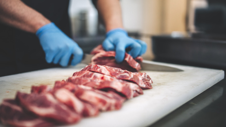 Hands slicing meat