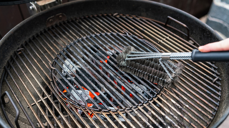 A person cleaning grill grates with a wire brush