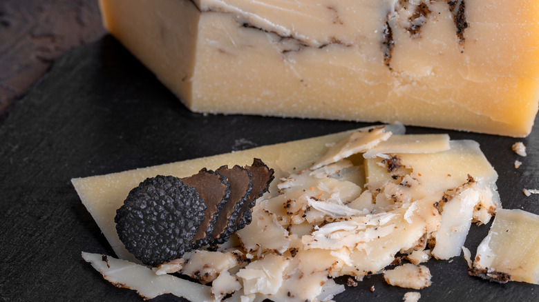 Pecorino Romano cheese on a slate with sliced black truffles to illustrate umami flavors