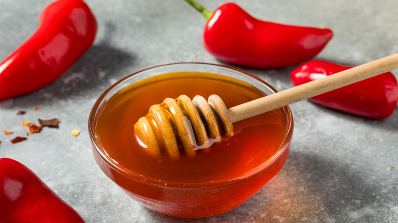 Hot honey in a bowl surrounded by chili peppers