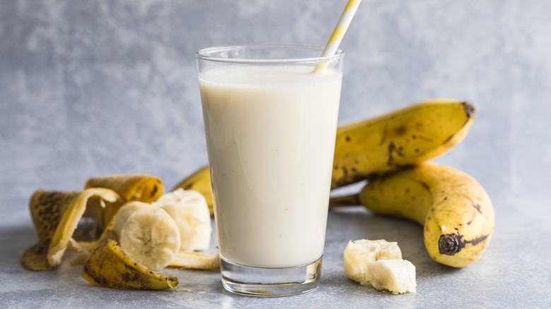 A blended banana agua fresca is in a glass with bananas in the background.