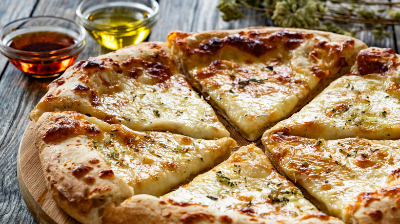 A cooked pizza bianca surrounded by oil and herbs