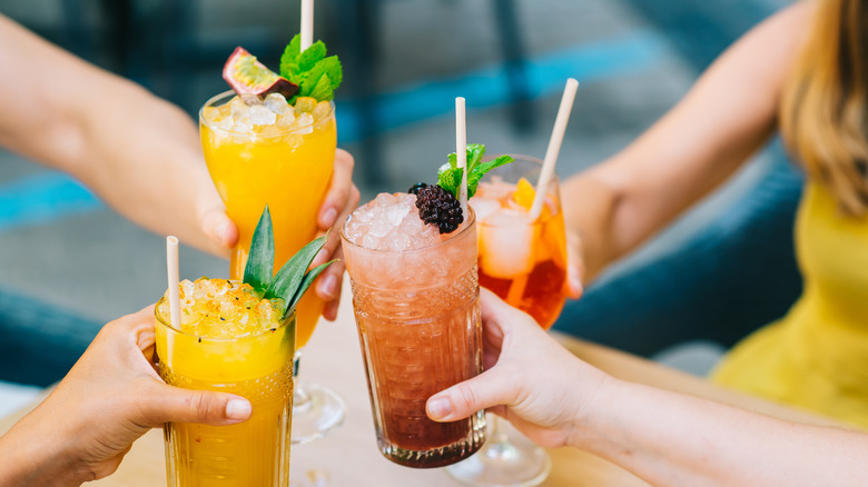 People clinking tropical cocktails together in the afternoon