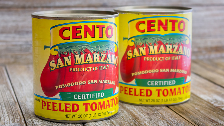 Two cans of Cento brand San Marzano tomatoes on a wooden table