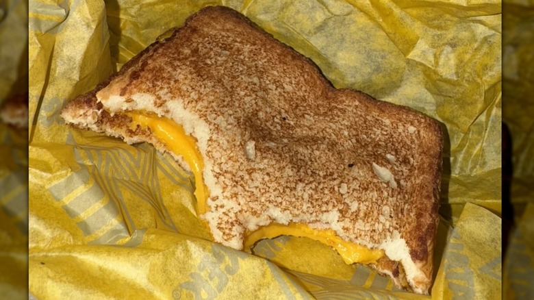 A bitten Whataburger grilled cheese sits on its wrapper