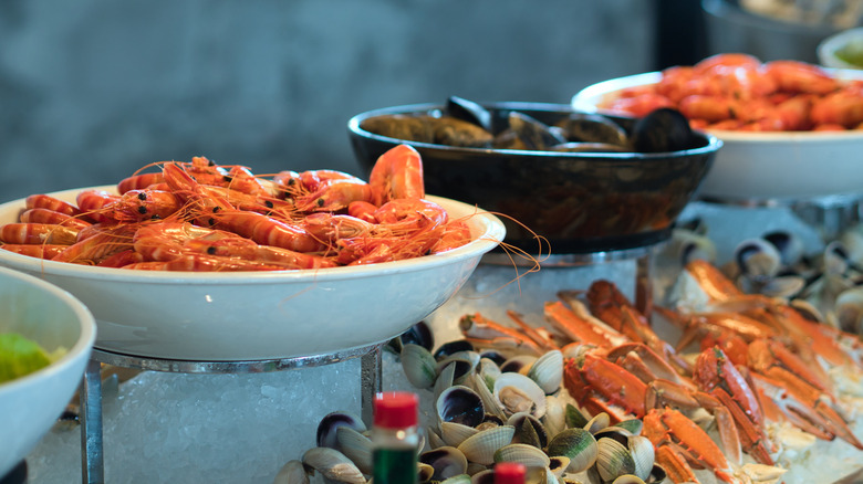 Crab legs, lobsters, and whole crabs sit on ice at a seafood buffet