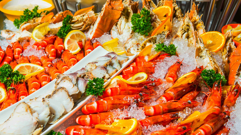 Shrimp and seafood sit in ice, garnished with lemon wheels, at a seafood buffet