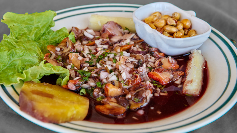 A plate of black clam ceviche with garnishes on the side