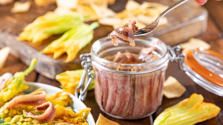 A jar of anchovies with a fork