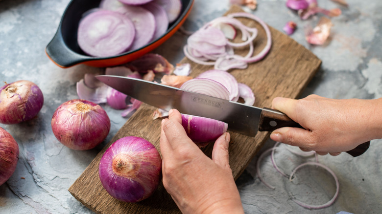 person slicing raw onions on cutting board