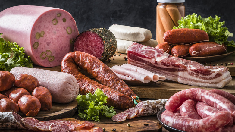 Different types of sausages and cured meats on wood cutting boards