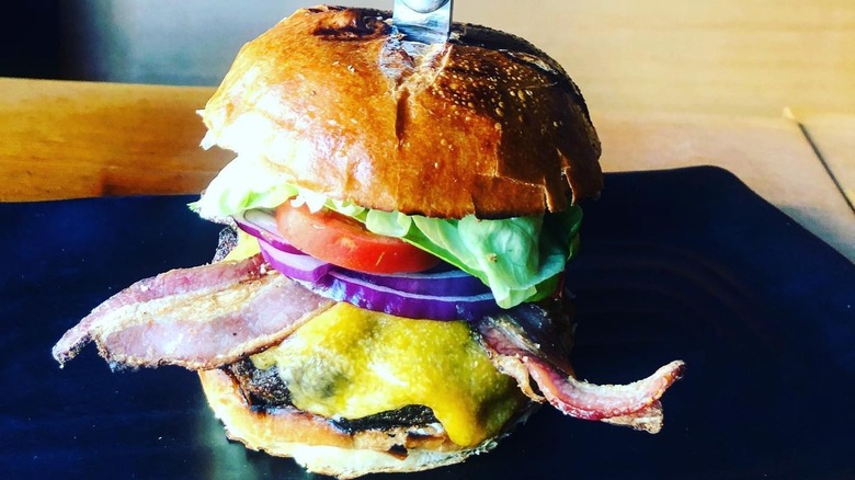 Burger with bacon, onions, lettuce, and tomato