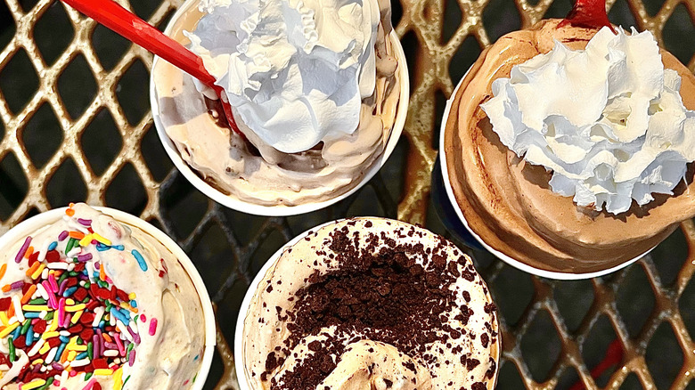 blizzards with sprinkles and whipped cream and one with chocolate crumbles