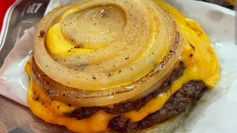 Two burger patties with cheese and grilled onions on top