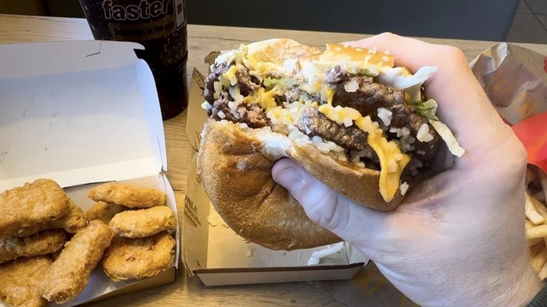 Hand holding a double cheeseburger dressed like a Big Mac