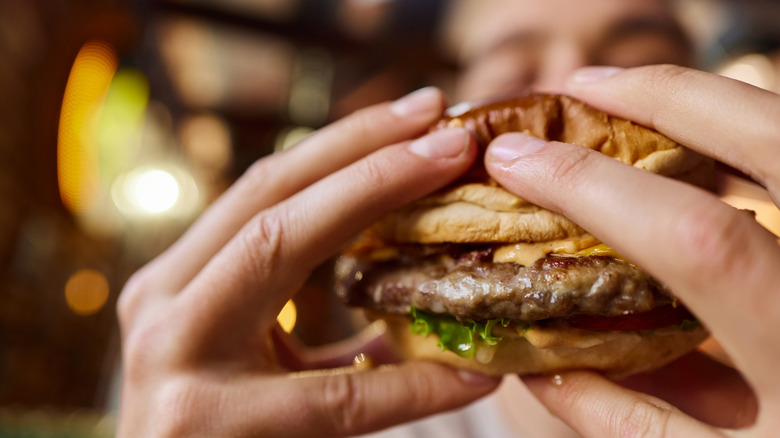 Hands holding a fast food burger with peanut butter