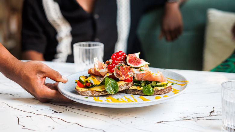 A restaurant server placing a plate on a marble tabletop