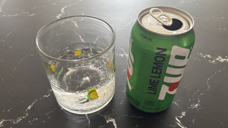 Glass of clear soda next to 7Up can