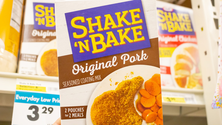 A box of Shake 'n Bake "Original Pork" seasoned coating mix, in front of a shelf of other boxes